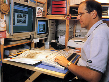 Eduard Bekker achter zijn computer die staat in de hal van zijn huis.