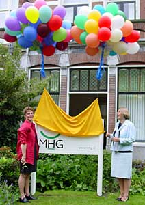 Medewerkster Anny Bronsveld en directeur Henriëtte Bertels onthullen met het oplaten van ballonnen het bord voor het nieuwe pand van de MHG aan de Johan Van Oldenbarneveltlaan.